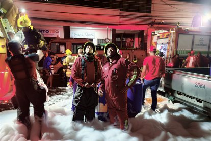 Personal de emergencia despliega espuma para sofocar el incendio en un local comercial del centro de Esmeraldas, durante una intensa operación nocturna.