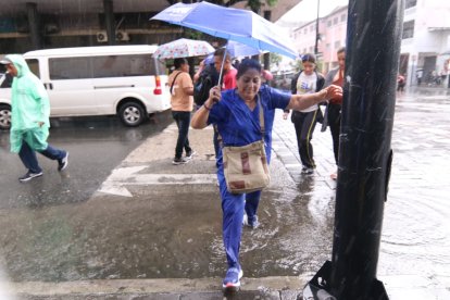 Ciudadanos esquivan las inundaciones por lluvias en el centro de Guayaquil.