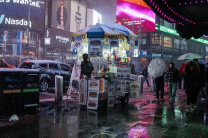 Un vendedor ambulante trabaja en su carrito de perritos calientes en Times Square durante la tormenta de nieve que azota Nueva York, Nueva York. EFE/Olga Fedorova