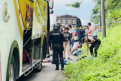 Agentes de la Policía custodian la unidad interprovincial en la vía La Concordia–Santo Domingo, mientras dos sospechosos permanecen en el suelo tras el asalto armado.