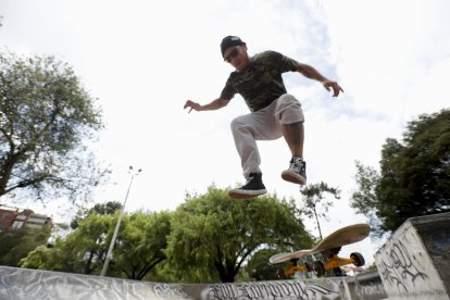 Precisión en el aire. El skater se eleva con precisión sobre el borde del parque, dominando la tabla en pleno salto, mientras el arte urbano y los árboles enmarcan una escena llena de energía y control.