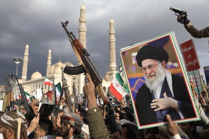 Partidarios hutíes sostienen sus armas y un retrato del líder supremo iraní, el ayatolá Alí Jamenei, durante una protesta