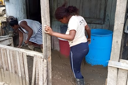 Los moradores sacan con baldes el lodo que ingresó a sus casas.