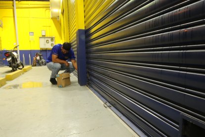 Una persona cierra un local tras el toque de queda este domingo, en Guayaquil (Ecuador).