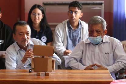 Luis Mancheno (i) conversa con el robot. Al fondo, estudiantes universitarios lo observan.