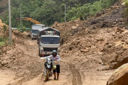 Con dificultad, conductores llevan vehículos por la carretera cubierta de lodo.
