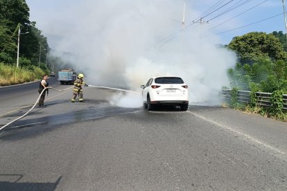 Dos bomberos de Esmeraldas trabajan en la extinción de un incendio vehicular en la vía de San Mateo. La rápida acción evitó que el fuego se expandiera.