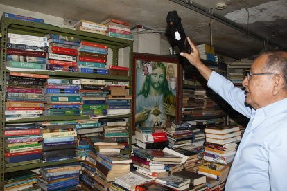 Fernando Balladares mientras busca entre sus pilos de libros textos escolares.
