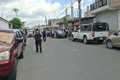 Vecinos y policías se concentran en una calle del sur de Esmeraldas, tras el asesinato de Henry Paúl Chila Mera dentro de una iglesia evangélica cercana.