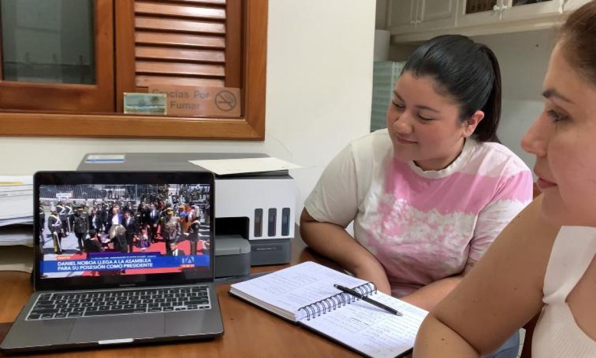 Geanella Altamarino (i) junto a su colaboradora Maitte Medina (d), observando la ceremonia en su laptop, en una oficina del negocio.