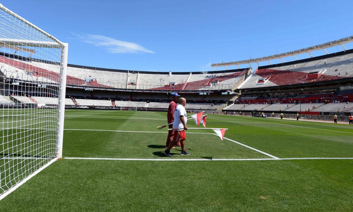 Members of the Monumental stadium ground staff pick up the corner fla