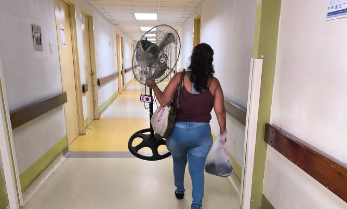 Una mujer lleva un ventilador para el cuarto del HTMC donde está su paciente.
