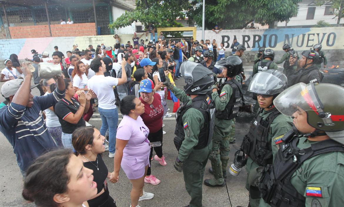 Personas reclaman frente a integrantes de la Guardia Nacional Bolivariana (GNB).