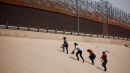 Referencial. Migrantes intentan cruzar el muro para ir a Estados Unidos.