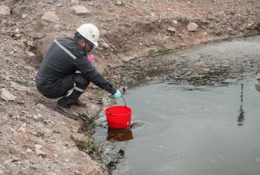 Una persona recoge el agua contaminada del río Daule.