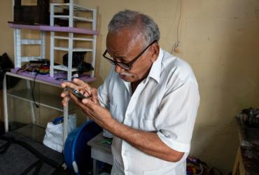 Víctor Guarín mientras mira su teléfono con ayuda de unos lentes, pero con una escasa visión.