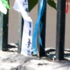 Algunos familiares que esperan noticias de sus parientes en las afueras del hospital se dan una vuelta por las rejas donde están los lazos.