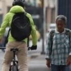 Un ciclista y un peatón comparten un espacio estrechito, a un lado de la reja.