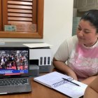 Geanella Altamarino (i) junto a su colaboradora Maitte Medina (d), observando la ceremonia en su laptop, en una oficina del negocio.