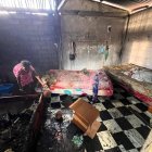 Una mujer revisa entre los restos calcinados de su vivienda, buscando entre las cenizas lo poco que el incendio dejó en pie.