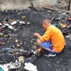  El pequeño Daniel (nombre protegido) busca entre los escombros quemados algún implemento que sirva para levantar el lugar.  