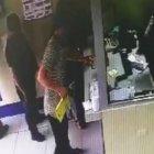  Imagen en que se ve a uno de los delincuentes, con la bolsa amarilla, exigiéndole a la cajera que le entregue el dinero. 