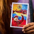  Fotografía de una mujer apoyando al presidente de Venezuela Nicolás Maduro mientras sostiene una imagen de Hugo Chavez. 