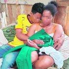  Gloria sostiene con sus manos el uniforme de colegio de su hijo muerto.  El mayor de sus vástagos la consuela con un abrazo. 