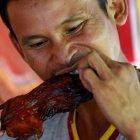  Decenas de ratas de campo aderezadas con especies se asan lentamente sobre las brasas. 