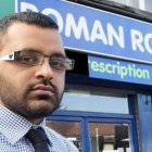  Metish Patel posando con su farmacia de fondo. 