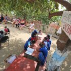 Génesis y Dennys Tola se reúnen con un grupo de niños debajo de un árbol.
