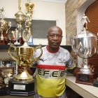 Ermen Benítez sostiene un par de trofeos, de los más de 200 que asegura haber ganado en su época de jugador.