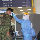 Personal del aeropuerto toma la temperatura de los pasajeros que llegan a la capital.