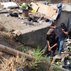 Miguel y Rolando caminan por un puente improvisado para entrar y salir de la covacha.