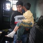 Agustín Daquilema carga a su hijo, quien sufrió quemaduras en una de sus extremidades.