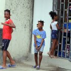 Un grupo de niños juega cerca de una tienda. Uno de ellos usa una pistola de juguete para divertirse.