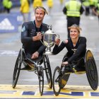 Marcel Hug (izq.) Y Manuela Schar de Suiza posan en la línea de meta con el trofeo después de ganar respectivamente las carreras en silla de ruedas masculina y femenina del 125 ° Maratón de Boston .