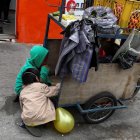 Niños acompañan a sus padres a trabajar con una carreta de productos vegetales en una calle de Quito.