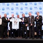Claudio Tapia (5-i) posando sosteniendo una camiseta de la selección argentina dedicada al fallecido Diego Maradona con el presidente de la FIFA, Gianni Infantino
