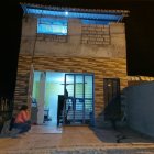 Una mujer pensativa fuera de la casa que fue tiroteada presuntamente por un prestamista.