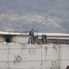 Sobre un muro del pabellón 2 se observa cómo se realizan pericias alrededor de un cadáver.