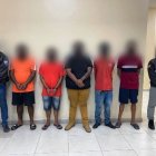 Dos policías escoltan a los 5 individuos arrestados en un operativo antidelictivo ejecutado en el suburbio de Guayaquil.
