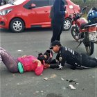 Un agente de tránsito trata de darle los primeros auxilios a la conductora caída.