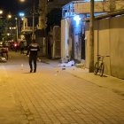 El cadáver de una de las víctimas yace al pie de la entrada de una vivienda, mientras un policía camina por el lugar.