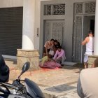 Familiares de la víctima lloran junto a su cadáver, al que han cubierto con sábanas, en la entrada de su casa.