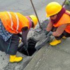 Dos mujeres de una de las microempresas realizan labores de limpieza en los drenajes de una de las vías de Tungurahua.