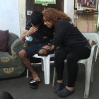 Las muletas soportan el físico del muchacho y su madre lo sostiene emocionalmente.