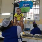 Lady Caicedo, comerciante del Mercado Oeste levanta a su pequeño sobrino, Lian, alentando a la Tricolor.