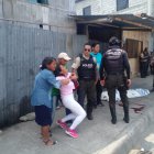 La mujer es contenida por un pariente. Ambos están cerca del cadáver.