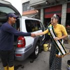 Un trabajador del lavado de vehículos en la zona detiene su actividad para saludar a la reina del club emblema de la barriada, el River Oeste.